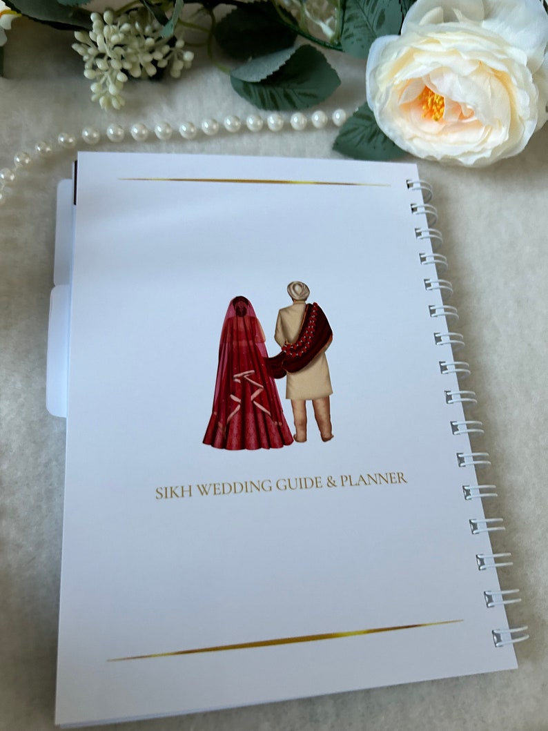May include: A white spiral bound notebook with a gold line at the top and bottom. The cover features a watercolor illustration of a bride and groom in traditional Sikh wedding attire. The text "SIKH WEDDING GUIDE & PLANNER" is printed in black below the illustration.