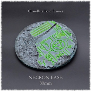 May include: A round, gray, textured, 80mm base with a green circuit board design. The base is designed for miniature wargaming.
