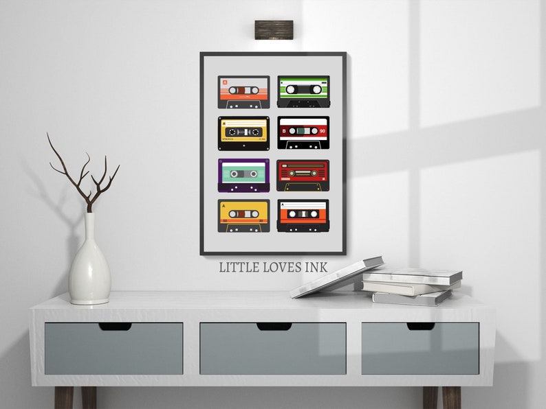 Puede incluir: Una impresi&oacute;n enmarcada con fondo blanco y marco negro que presenta una colecci&oacute;n de nueve cintas de cassette de colores. El texto "LITTLE LOVES INK" est&aacute; impreso debajo de la imagen.