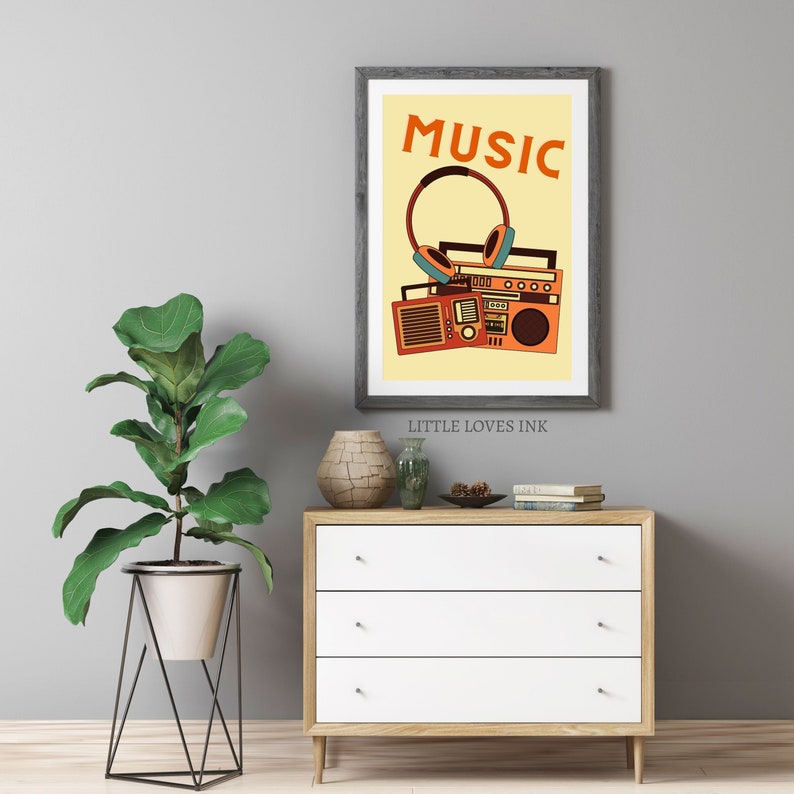 May include: A vintage-style print with a boombox, headphones, and the word "MUSIC" in orange on a yellow background. The print is framed in gray and has the text "LITTLE LOVES INK" below the image.