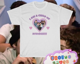 May include: White t-shirt with a pink heart graphic featuring a group of people and the text "I am a child of divorce!!!". The heart graphic has a pink outline and the text is in purple. The t-shirt is on a person's chest.