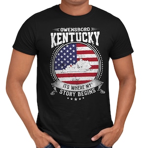 May include: Black t-shirt with a distressed white graphic of the state of Kentucky and a US flag. The text "Owensboro Kentucky" and "It's where my story begins" is printed on the shirt.