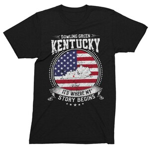 Może przedstawiać: Czarny T-shirt z przetartym wzorem amerykańskiej flagi przedstawiającym stan Kentucky i tekst "Bowling Green Kentucky It's Where My Story Begins".