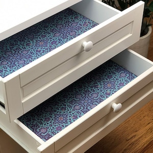 May include: Two white drawers with blue and purple patterned drawer liners. The drawers are open and the liners are visible.