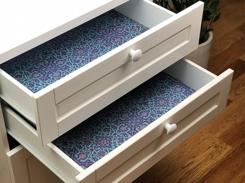 May include: Two white drawers with blue and purple patterned drawer liners. The drawers are open and the liners are visible.