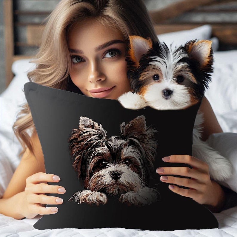 May include: A black throw pillow with an embroidered image of a Yorkshire Terrier dog peeking out from behind the pillow. The dog has brown, black, and white fur.