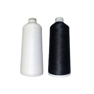 May include: Two spools of thread, one white and one black, are displayed against a white background. The spools are cylindrical with a conical top, and the thread is tightly wound around them. The white spool has the word "MADEIRA" printed on the top.