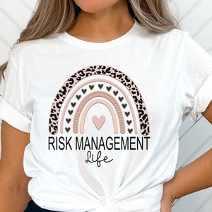 May include: White t-shirt with a pink and brown rainbow design with black leopard print accents. The rainbow has small pink hearts and the text "RISK MANAGEMENT life" is below the rainbow.