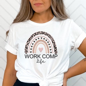 May include: White t-shirt with a pink and brown rainbow design featuring leopard print and hearts. The text "WORK COMP life" is printed below the rainbow.