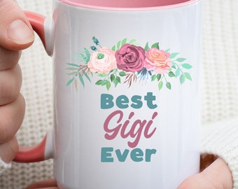 May include: A white ceramic mug with a pink interior and handle. The front features a floral arrangement in shades of pink, purple, and green above the text Best Gigi Ever, with Best and Ever in teal and Gigi in a script pink font.