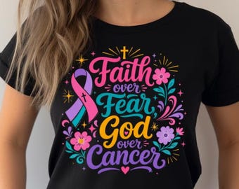 May include: A black short-sleeved t-shirt featuring a colorful graphic with the text Faith over Fear God over Cancer, a multi-colored awareness ribbon, a small cross, and various floral elements in pink, blue, and purple hues.