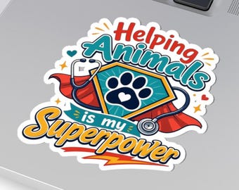 May include: A die-cut sticker featuring a teal shield with a black paw print, a red cape, and a silver stethoscope. The text reads Helping Animals is my Superpower in red, teal, and yellow lettering with small hearts and stars.