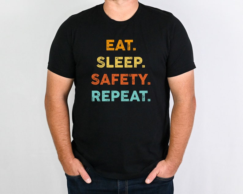 May include: A black t-shirt with a vintage-style graphic that reads "EAT. SLEEP. SAFETY. REPEAT."