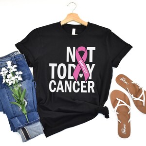 May include: Black t-shirt with the text "Not Today Cancer" and a pink ribbon with the word "Breast" on it.