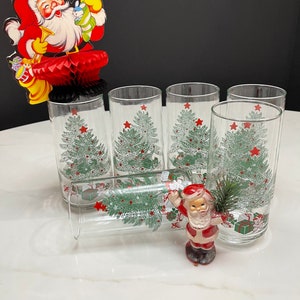 May include: Set of six clear glass tumblers with a Christmas tree design. The glasses feature a green Christmas tree with red stars and presents.