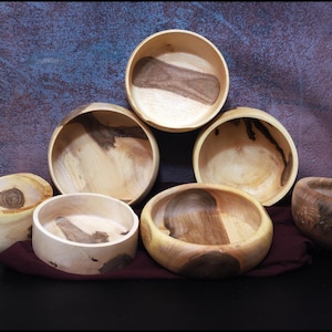 Peut inclure: Une collection de bols en bois faits à la main de différentes tailles et formes. Les bols présentent des motifs de grain de bois naturels avec des teintes marron clair et foncé. Certains bols ont des formes organiques uniques.