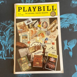May include: A vintage Playbill magazine cover from April 1984, featuring a collage of various Broadway show posters and advertisements. The magazine's title is prominently displayed in yellow lettering, with the tagline "The National Theatre Magazine" underneath. The cover is adorned with images of iconic Broadway productions, including "Oklahoma!" and "Life with Father".