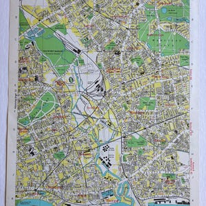May include: A vintage printed map of North-East London featuring a grid system with numbered and lettered coordinates. The map displays streets, parks in green, residential areas in yellow, and the River Thames in blue with black text labels.