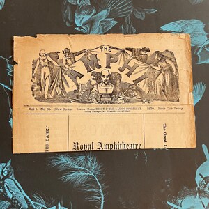 May include: A vintage black and white illustration of a theater stage with the words "The Amphitheatre" in a banner above the stage. The text "Vol 1. No. Co. (New Series) Lensees Mensca HENRY LIBLIE & LINDO COURTESAY. 1879. Price One Penny. Acting Manager, Mr CHARLES COURTENAY" is printed below the stage. The text "Royal Amphitheatre" is printed below the illustration.