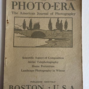 May include: A vintage copy of "PHOTO-ERA," The American Journal of Photography, from December 1908. The cover displays a landscape illustration with a bridge and trees. The magazine's cover is tan with black text, including the price of 15 cents.