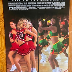 May include: A movie poster for the film "Bring It On" featuring a group of cheerleaders in red and green uniforms performing a cheer routine on a basketball court. The poster includes the title "Bring It On" and the tagline "May the best moves win."