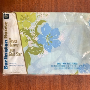 Könnte beinhalten: Eine Verpackung für ein Einzelbett-Flachbettlaken von Burlington House. Das Laken besteht aus 50% Baumwolle und 50% Kodel-Polyester. Die Verpackung zeigt ein blaues und grünes Blumenmuster. Der Text auf der Verpackung lautet "Never Never Iron Gold Star" und "Stays fresh longer". Die Verpackung enthält auch die Größe des Bettkastens: "One Twin Flat Sheet for mattress from 30 x 75 in. to 39 x 75 in. (72 x 104 in. size before hemming)".