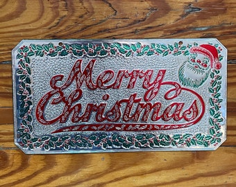 Placa de matrícula vintage de mediados de siglo &quot;Feliz Navidad&quot;, fina lámina metálica en relieve con Papá Noel y acebo.