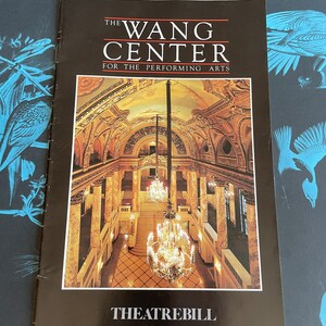 Könnte beinhalten: Eine schwarz-weiße Broschüre für das Wang Center for the Performing Arts. Die Broschüre zeigt ein Foto des Theaterinnenraums mit einem großen Kronleuchter, der von der Decke hängt. Der Text "THE WANG CENTER FOR THE PERFORMING ARTS" ist oben auf der Broschüre gedruckt. Der Text "THEATREBILL" ist unten auf der Broschüre gedruckt.