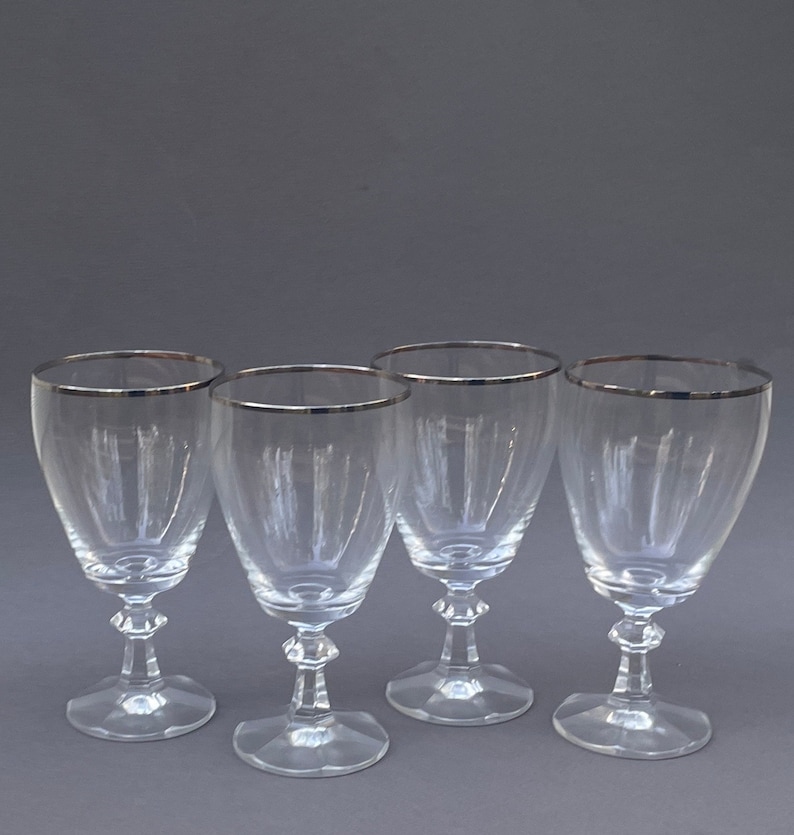 May include: Set of four clear glass wine glasses with a silver rim.