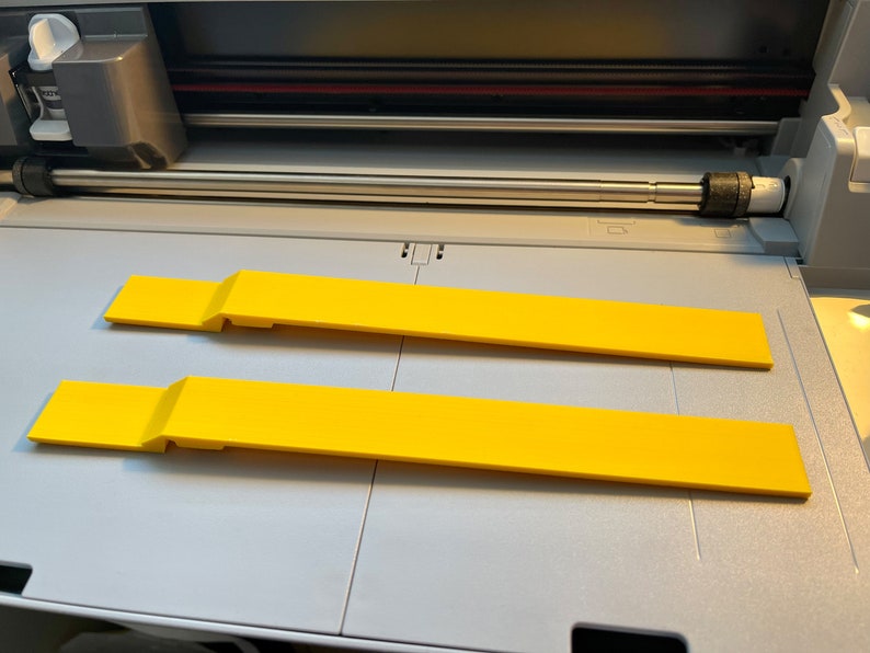 May include: Two yellow plastic cutting mats for a craft cutter. The mats are on a gray surface.