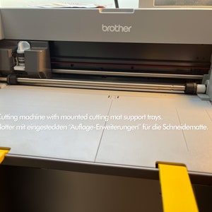 May include: A gray Brother cutting machine with yellow cutting mat support trays. The machine has a silver cutting blade and a white cartridge.
