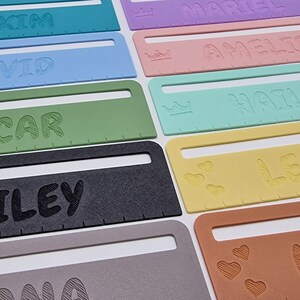 Pode incluir: Um conjunto de r&eacute;guas personalizadas coloridas com diferentes nomes e elementos decorativos. As r&eacute;guas s&atilde;o de pl&aacute;stico e t&ecirc;m um fundo branco. Os nomes s&atilde;o impressos em preto e os elementos decorativos s&atilde;o de diferentes cores. Os nomes nas r&eacute;guas s&atilde;o: Maxim, David, Oscar, Hailey, Amelie, Harley, Leonie, Marina.