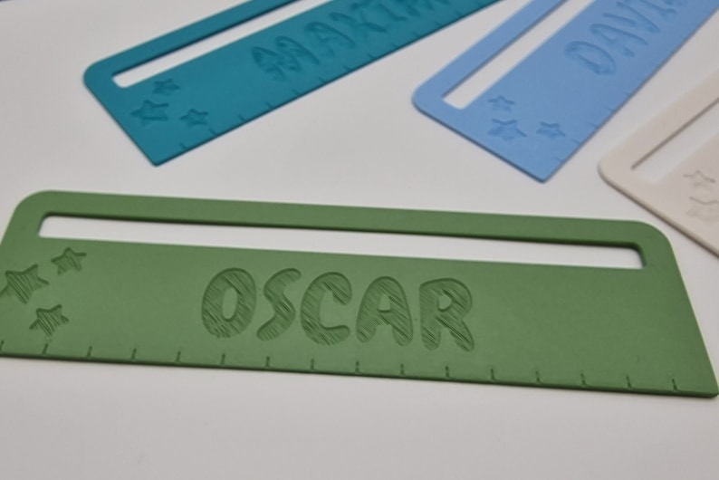 Pode incluir: Uma r&eacute;gua personalizada verde com o nome "OSCAR" em relevo em branco. A r&eacute;gua tem uma pequena janela na parte superior e cinco estrelas brancas no lado esquerdo.