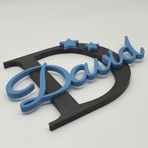 May include: A blue wooden name sign with the name "David" in a cursive font. The name is attached to a black wooden letter "D". Two blue stars are placed above the name.
