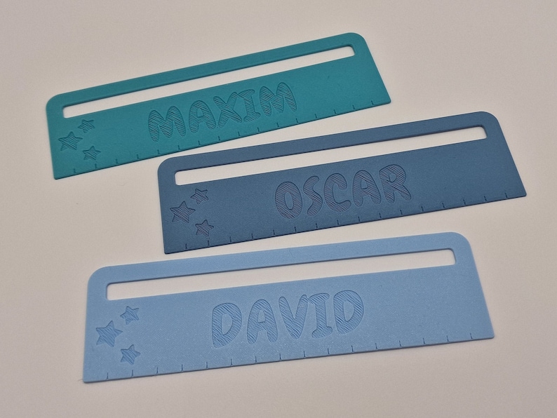 Pode incluir: Tr&ecirc;s r&eacute;guas de pl&aacute;stico azuis com os nomes "Maxim", "Oscar" e "David" impressos nelas. Cada r&eacute;gua tem uma fila de estrelas e uma escala de r&eacute;gua.