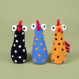 May include: Three felt toy chickens with different colored polka dots. The chicken on the left is black with white polka dots, the middle chicken is blue with orange polka dots, and the chicken on the right is yellow with black polka dots.