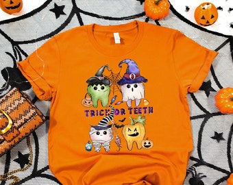 May include: Orange t-shirt with a Halloween themed design featuring cartoon teeth dressed as ghosts and witches. The text "Trick or Teeth" is printed on the shirt.
