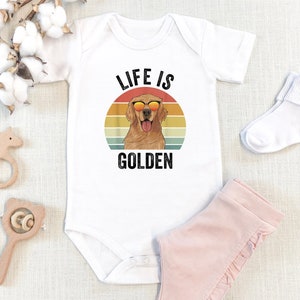 May include: White baby onesie with a retro-style graphic of a golden retriever wearing sunglasses. The graphic says "Life is Golden".