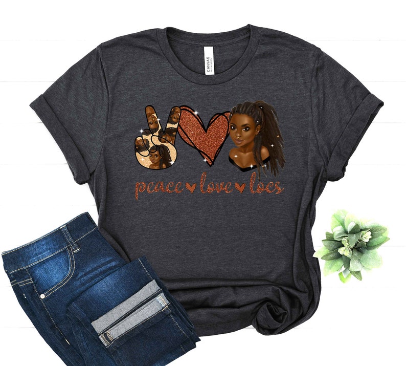May include: A dark gray t-shirt with a peace sign, heart, and a woman with locs. The design is in glitter and says "peace love locs".