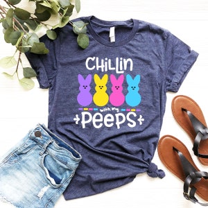 May include: A navy blue t-shirt with the text "Chillin with my peeps" and four colorful marshmallow Peeps.