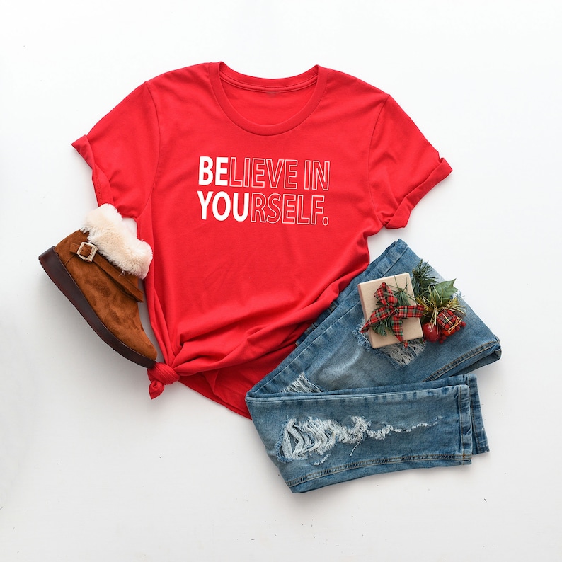 Może przedstawiać: Czerwony T-shirt z białym napisem "WIERZ W SIEBIE."