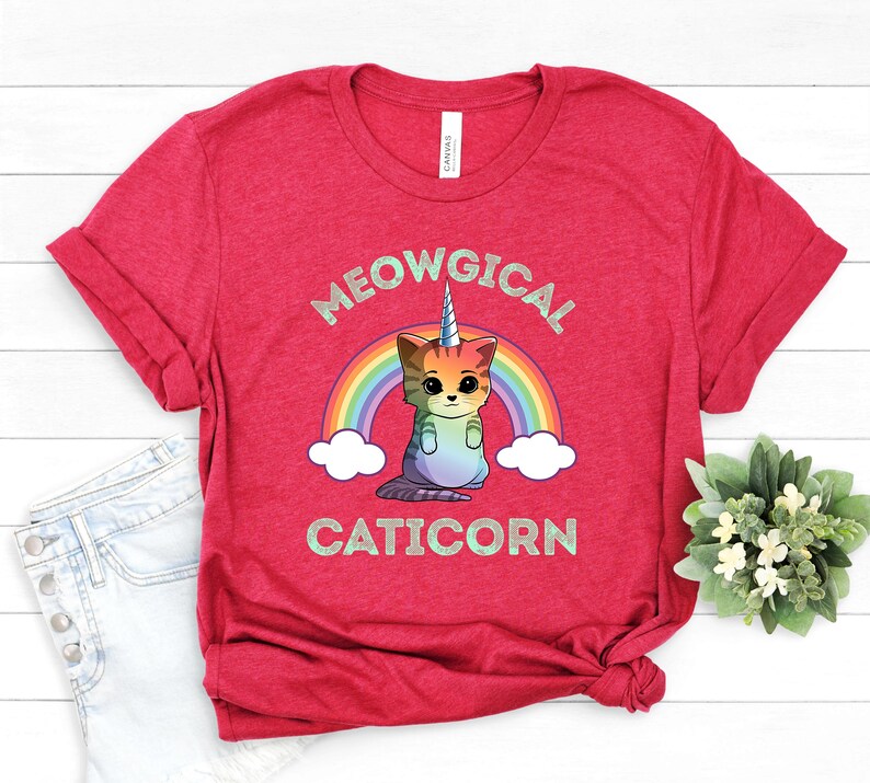 May include: Red t-shirt with a rainbow and a caticorn graphic. The text "MEOWGICAL CATICORN" is printed on the shirt.