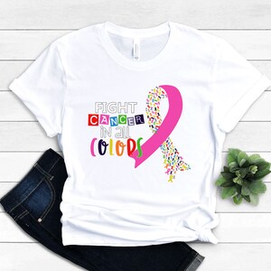 Puede incluir: Camiseta blanca con una cinta rosa hecha de cintas m&aacute;s peque&ntilde;as de colores. El texto "FIGHT CANCER in all COLORS" est&aacute; impreso en la camiseta.
