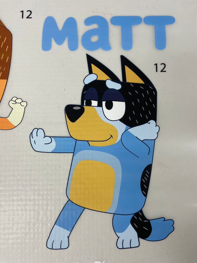 May include: A cartoon illustration of a blue dog character with black and white markings, striking a pose. The name "MATT" is written in blue letters above the dog. The number "12" appears twice in the image.