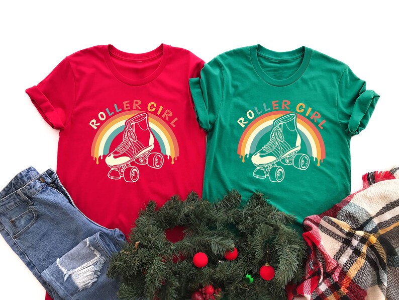 Peut inclure: Deux t-shirts rouge et vert avec le texte "Roller Girl" et un graphique arc-en-ciel avec un patin &agrave; roulettes.