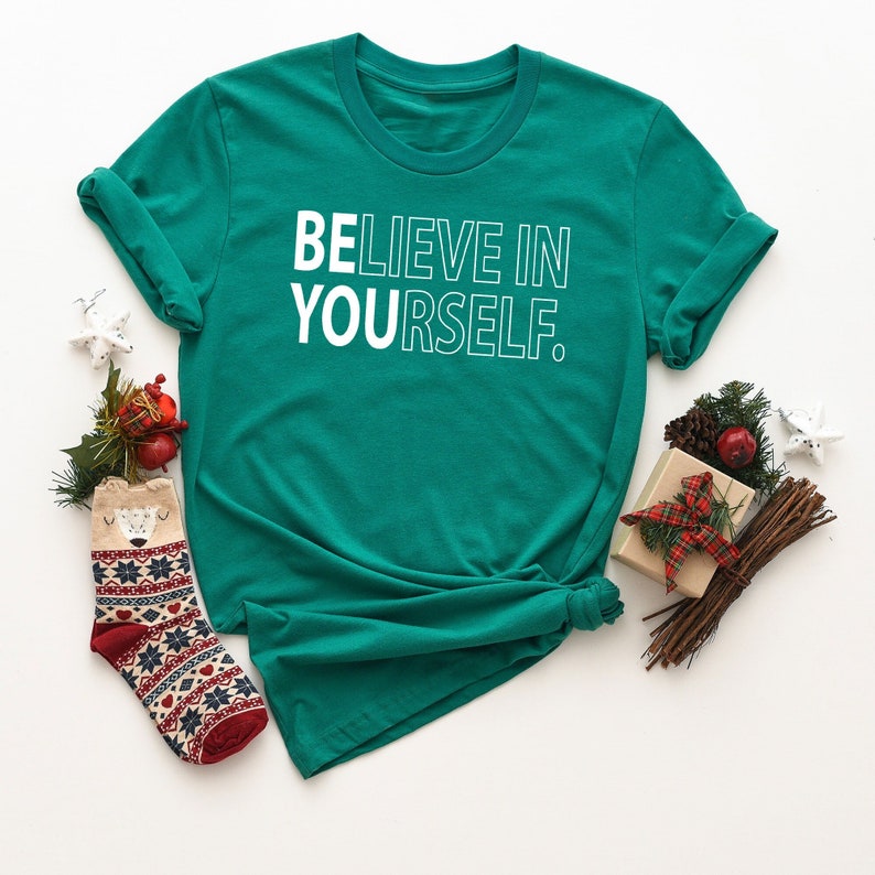 Może przedstawiać: Zielony t-shirt z nadrukiem "BELIEVE IN YOURSELF" w kolorze białym.
