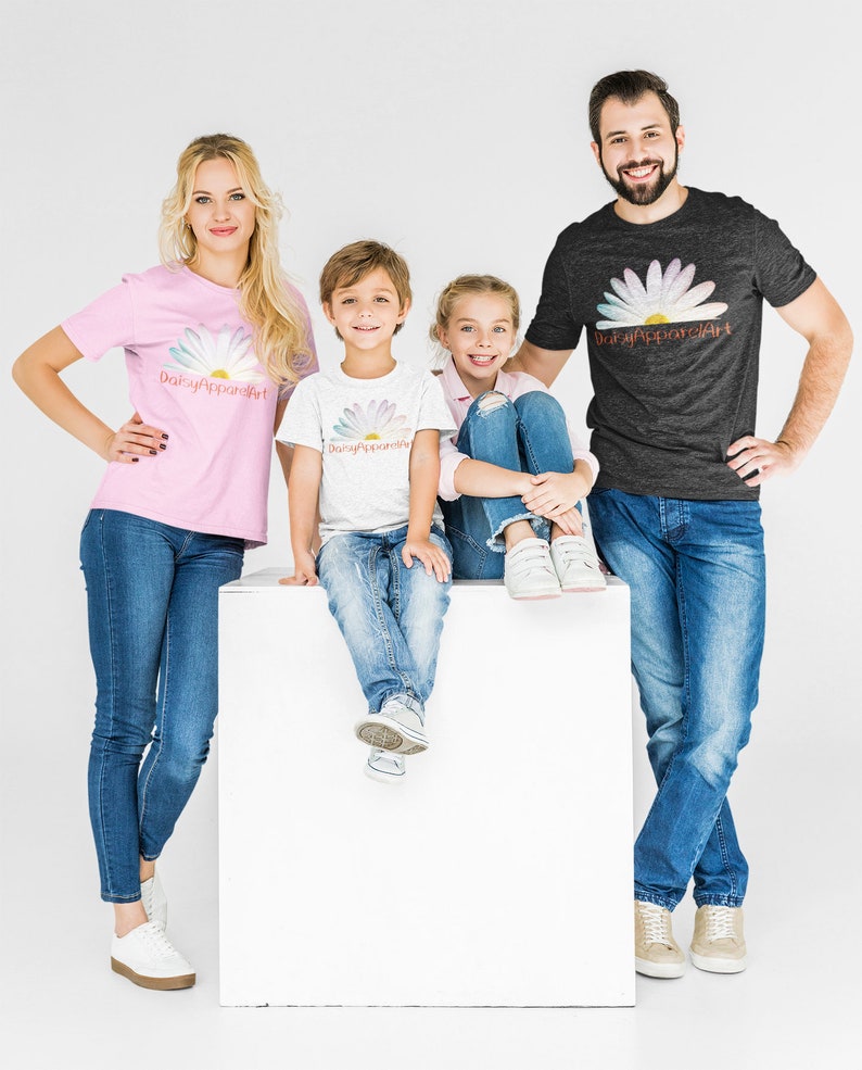 May include: A family of four wearing matching t-shirts with a daisy and the text "DaisyApparelArt". The family is standing in front of a white background. The father is wearing a dark grey t-shirt, the mother is wearing a pink t-shirt, and the two children are wearing white t-shirts.