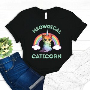 May include: Black t-shirt with a rainbow and a cat with a unicorn horn. The text "MEOWGICAL CATICORN" is printed on the shirt.