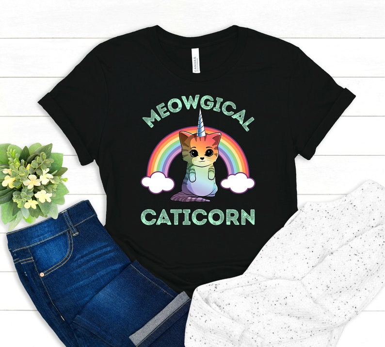 May include: Black t-shirt with a rainbow and a cat with a unicorn horn. The text "MEOWGICAL CATICORN" is printed on the shirt.
