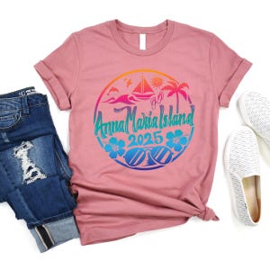 Puede incluir: Una camiseta rosa con un dise&ntilde;o gr&aacute;fico colorido de una escena de playa con el texto "Anna Maria Island 2025".